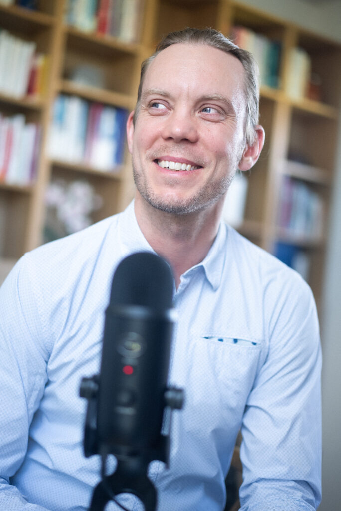 Portræt af Rasmus Thy Grøn med mikrofon i forgrunden.